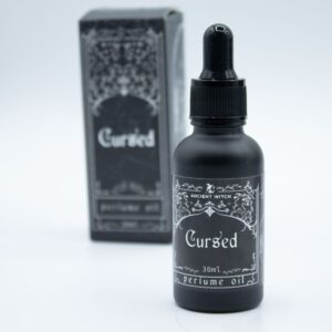 Frasco negro mate de aceite de perfume Maldito de 30 ml con cuentagotas junto a su caja negra ilustrada