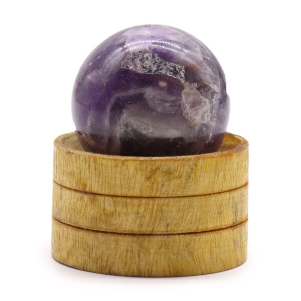 Esfera de amatista africana con zonas violetas y claras sobre un soporte de madera