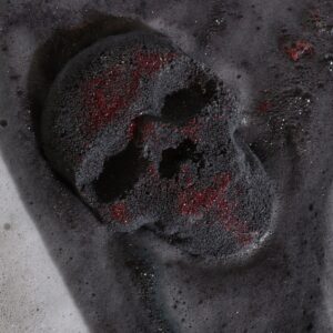 Bomba de baño con forma de calavera negra salpicada de brillo rojo