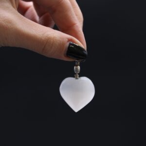 Colgante de selenita blanca en forma de corazón con anilla en la parte superior, sobre fondo blanco