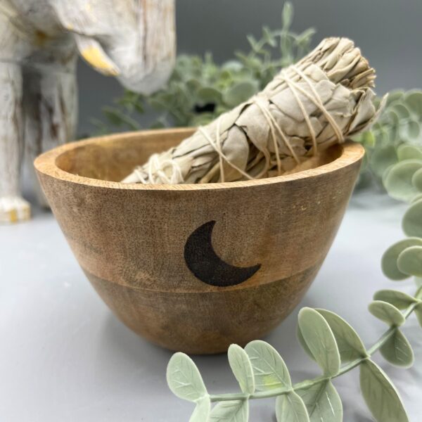 Cuenco de madera de mango con una media luna negra en el costado y un atado de salvia dentro