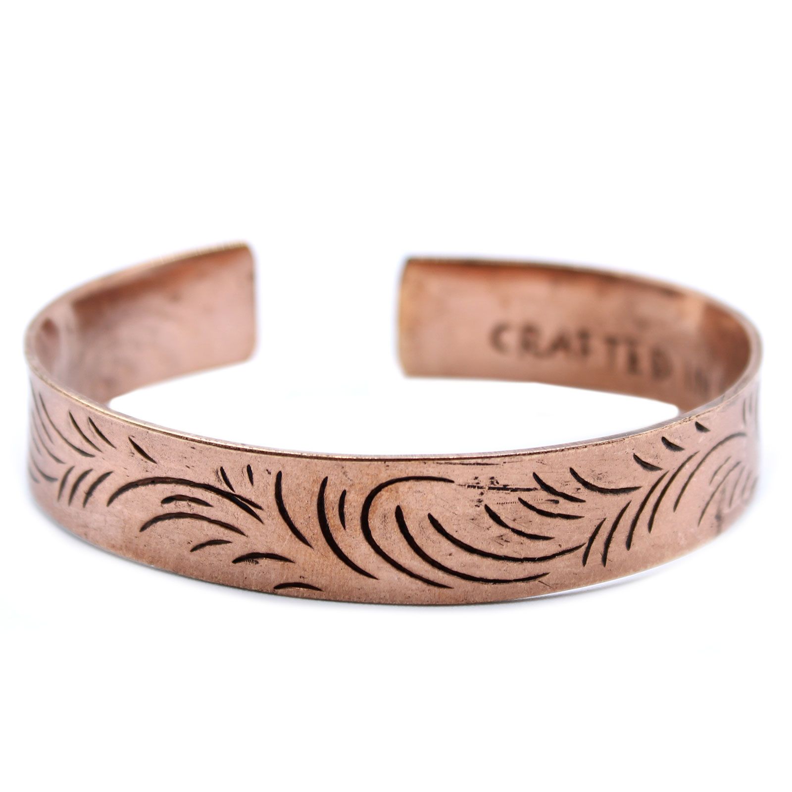 Pulsera abierta de cobre con remolinos grabados en la cara exterior