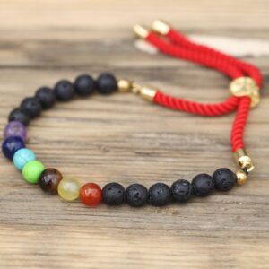 Pulsera de cordón rojo trenzado con cuentas de lava negra, siete cuentas de colores de los chakras y pasador dorado