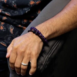 Dos pulseras de amatista en la muñeca: una elástica de cuentas y otra de cordón ajustable