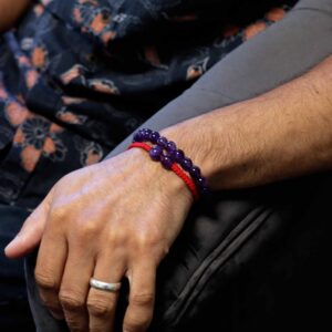 Dos pulseras de amatista en la muñeca: una elástica de cuentas y otra de cordón ajustable