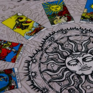 Tapete gris de tarot con un sol de ojos cerrados en el centro y doce cartas del tarot a color alrededor