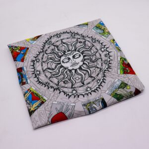Tapete gris de tarot con un sol de ojos cerrados en el centro y doce cartas del tarot a color alrededor
