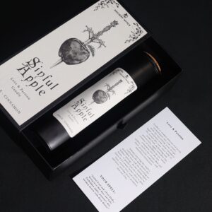 Vela ritual Manzana pecaminosa en vaso negro junto a su caja con una manzana atravesada por un puñal