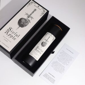 Vela ritual Manzana pecaminosa en vaso negro junto a su caja con una manzana atravesada por un puñal