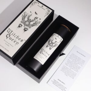 Vela ritual Reina de las brujas en vaso negro junto a su caja con una corona de ramas y polillas