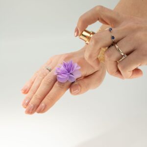 Anillo con flor de gasa color lavanda de varias capas sobre banda elástica negra