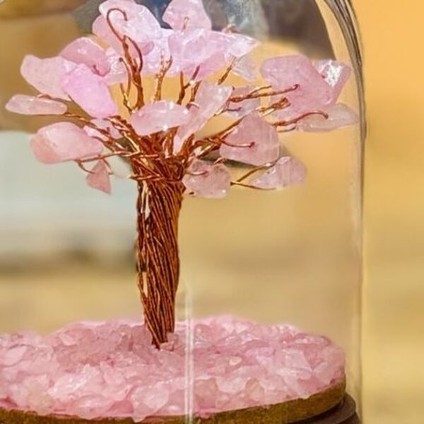Árbol de lascas de cuarzo rosa con tronco de alambre de cobre bajo una cúpula de cristal sobre base de madera