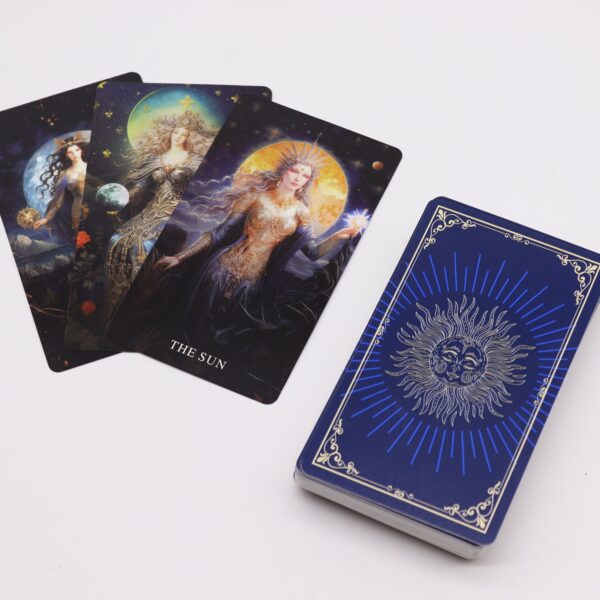 Cartas de tarot con diosas ilustradas sobre cielos nocturnos, entre ellas El Sol, junto al mazo con reverso azul y un sol de ojos cerrados