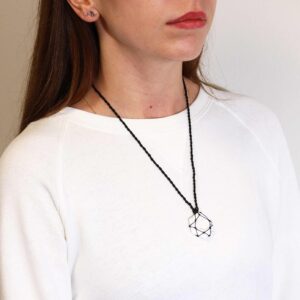 Hexágono de howlita blanca veteada de gris con una estrella de hilo negro anudado encima