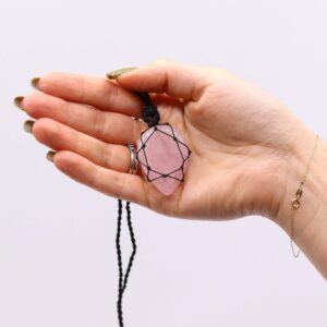 Gota de cuarzo rosa pálido envuelta en una estrella de nudos de cordón negro, con su cordón