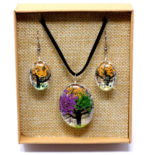 Colgante y pendientes ovalados de vidrio con un árbol de la vida de flores prensadas lilas, verdes y naranjas, en su caja