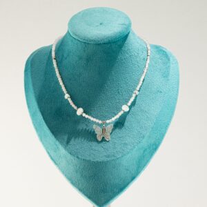 Collar de cuarzo rosa pálido en cuentas facetadas, con lascas lechosas y una mariposa metalizada sobre una hoja natural