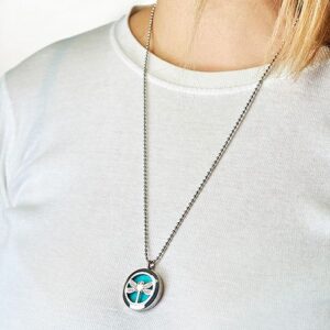 Collar difusor de acero con una libélula calada sobre almohadilla turquesa y cadena de bolas