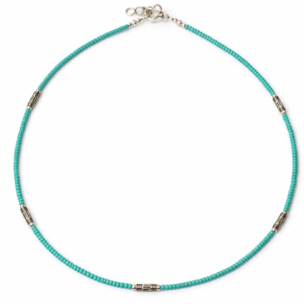 Collar fino de cuentas diminutas color turquesa con tubitos metálicos grabados en tono plateado, sobre fondo blanco