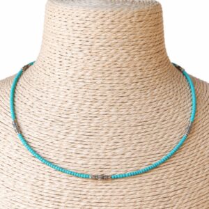 Collar fino de cuentas diminutas color turquesa con tubitos metálicos grabados en tono plateado, sobre fondo blanco