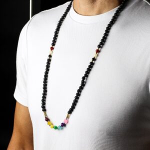 Hombre con camiseta blanca y un collar largo de lava volcánica con una hilera de cuentas facetadas de colores