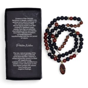 Collar largo de cuentas de lava negra y cuentas rojas con colgante ovalado de piedra rojiza envuelto en alambre dorado, junto a su caja