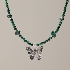 Collar de cuentas facetadas de malaquita verde con lascas pulidas y una mariposa plateada que conserva los nervios de una hoja real