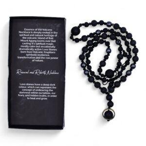 Collar negro de cuentas de piedra de lava y cuentas facetadas con colgante de una cuenta de lava dentro de un aro dorado, junto a su caja