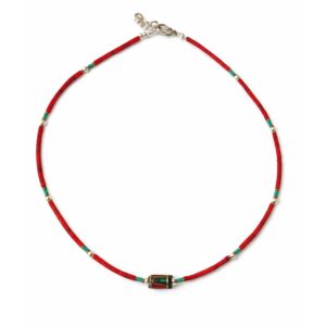 Collar fino de cuentas rojo coral con toques turquesa y una cuenta central dorada con incrustaciones, puesto en un busto de rafia