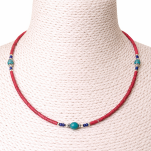 Collar fino de tubitos rosa coral con vetas y cinco cuentas redondas color turquesa entre rondeles plateados y cuentecitas azul oscuro, sobre fondo blanco