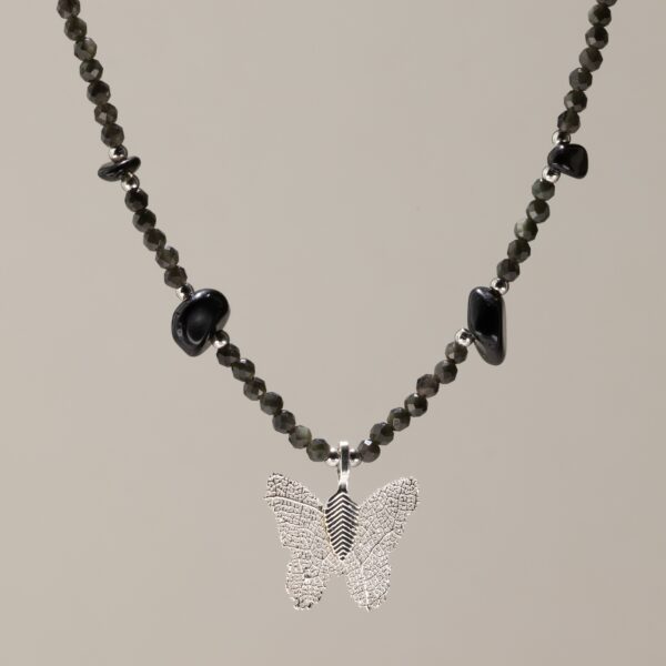 Collar negro de obsidiana facetada y lascas pulidas alrededor de una mariposa con baño de plata y nervadura de hoja