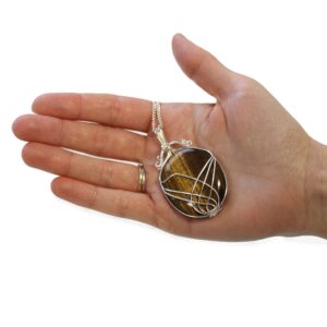 Collar de ojo de tigre pulido en óvalo, marrón y dorado, sujeto con hilos de alambre plateado cruzados en arcos, con cadena