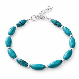 Conjunto de collar y pulsera de cuentas alargadas de howlita teñida color turquesa con vetas oscuras y bolitas plateadas, en un busto