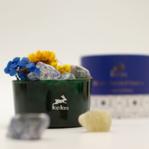 Tarro de vidrio verde con sodalita en bruto azul y blanca y flores secas amarillas y azules