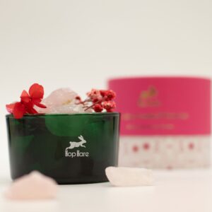 Tarro de vidrio verde con trozos de cuarzo rosa en bruto y flores secas rojas y rosas