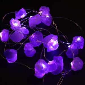 Guirnalda de luces LED encendida con trozos de amatista en bruto violetas sobre fondo negro