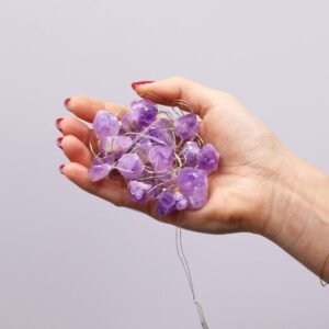 Guirnalda de luces LED encendida con trozos de amatista en bruto violetas sobre fondo negro