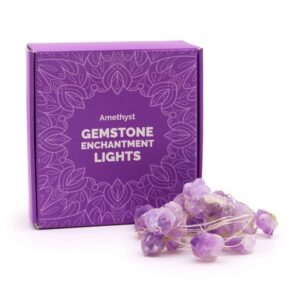 Guirnalda de luces LED encendida con trozos de amatista en bruto violetas sobre fondo negro