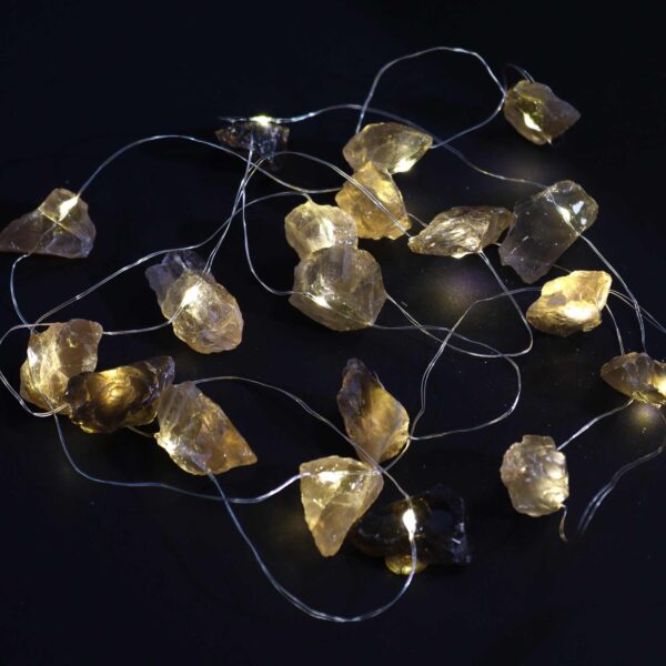 Guirnalda de luces LED encendida con piedras de citrino ahumado en bruto, grises y doradas, sobre fondo negro