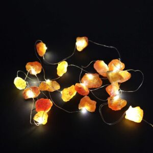 Guirnalda de luces LED encendida con piedras naranjas en bruto sobre fondo negro