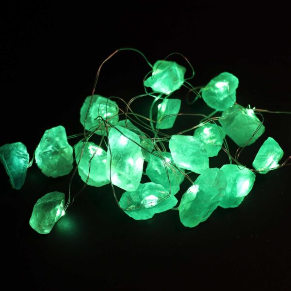 Guirnalda de luces LED encendida con piedras verdes translúcidas en bruto sobre fondo negro