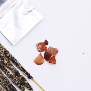 Varillas de incienso de azafrán hechas a mano junto a una bolsita y trocitos de ágata roja