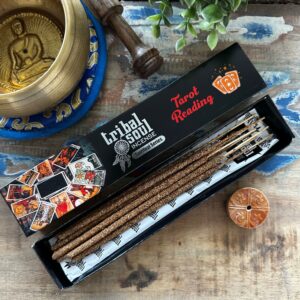 Caja negra de incienso ilustrada con cartas de tarot, abierta, con varillas y soporte redondo de cerámica naranja