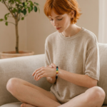Modelo pelirroja con una pulsera de cuentas de los siete chakras, junto a velas de colores encendidas