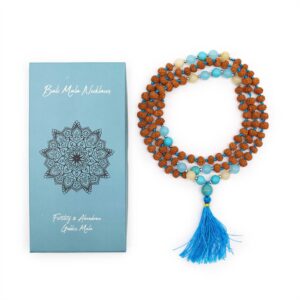 Mala de semillas de rudraksha anudado con hilo turquesa, cuentas turquesa, azul agua y amarillo pálido y borla azul, junto a su caja