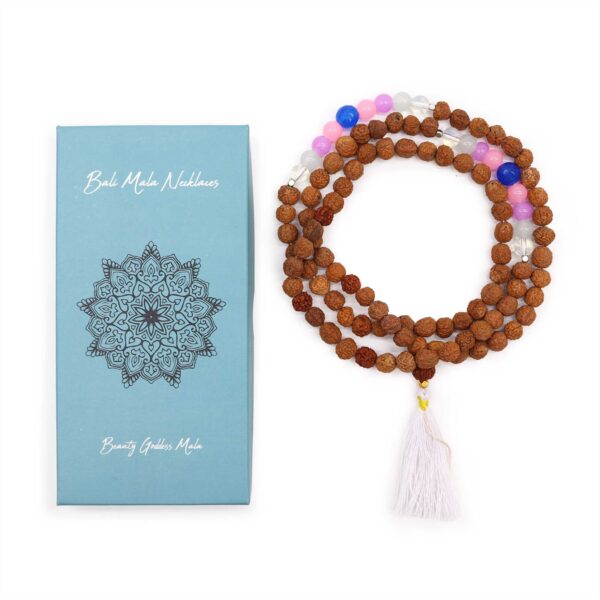 Mala de semillas de rudraksha con cuentas rosas, lilas, azules y blancas y borla blanca, junto a su caja turquesa con mandala