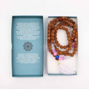 Mala de semillas de rudraksha con cuentas rosas, lilas, azules y blancas y borla blanca, junto a su caja turquesa con mandala