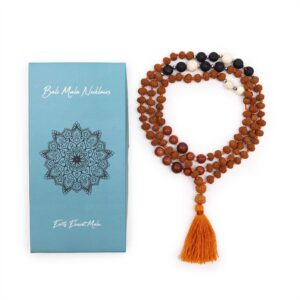 Mala de semillas de rudraksha anudado con hilo naranja, cuentas negras de piedra volcánica, cuentas blancas y marrones y borla naranja, junto a su caja