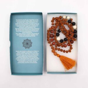 Mala de semillas de rudraksha anudado con hilo naranja, cuentas negras de piedra volcánica, cuentas blancas y marrones y borla naranja, junto a su caja