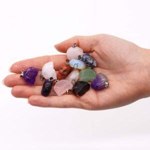 Doce colgantes de calavera tallados en piedra con asa plateada sobre una mano: amatista, cuarzo rosa, aventurina, sodalita, jaspe rojo, cristal de roca y opalita